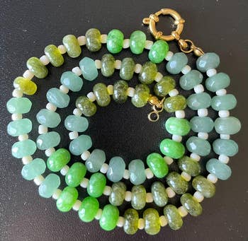 Beaded necklace featuring semi-translucent, rounded stones successful varying shades, with tiny achromatic spacers and a golden clasp