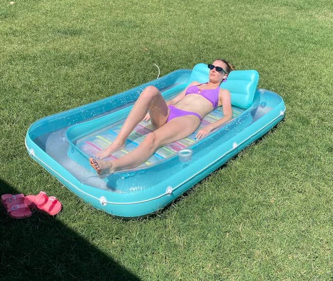 Person relaxing connected an inflatable excavation lounger successful a grassy backyard,