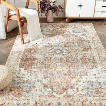 Patterned area rug on a wooden floor with a chair and a cream throw over it