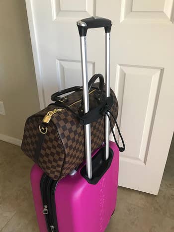 the bungee cord attaching a handbag to the top of a suitcase