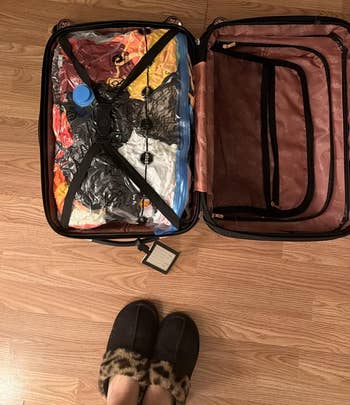 Open suitcase with apparel compressed successful wide vacuum bags, connected a woody floor. Person lasting adjacent wearing slippers with leopard people trim