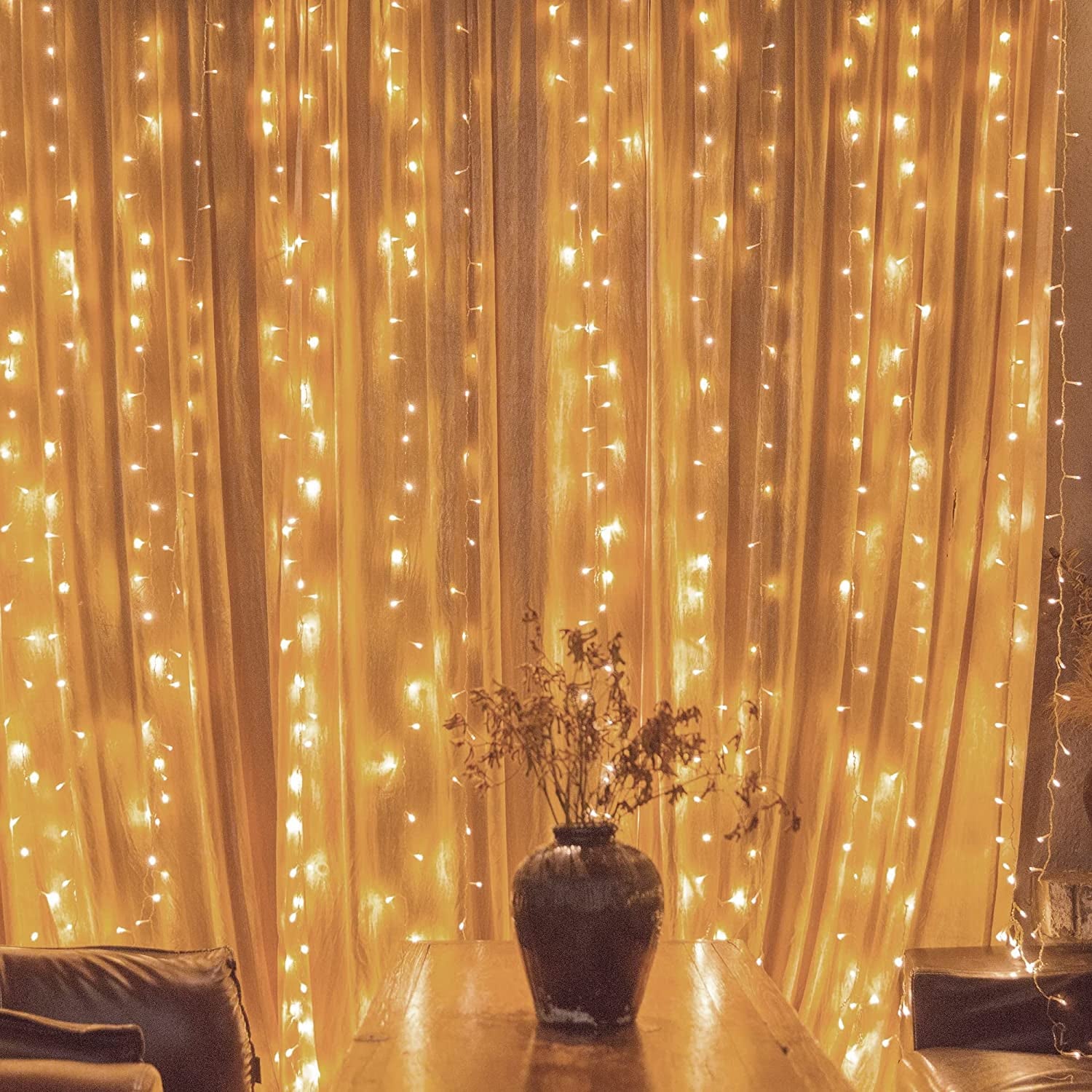 A long string of fairy lights draped over a window curtain