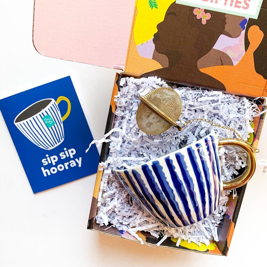 a box with a pretty mug, tea diffuser, and card that says