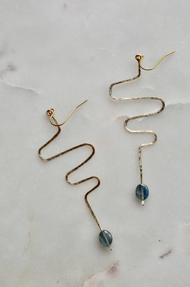 shot of brass squiggle earrings with blue stones at the base
