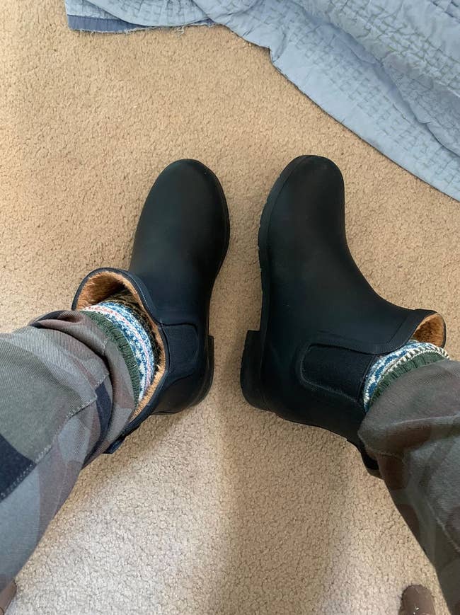 Person wearing achromatic boots with cozy patterned socks and camo pants, lasting connected carpet