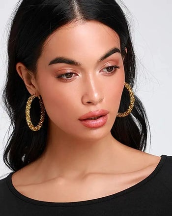 a model wearing chunky gold glitter hoop earrings