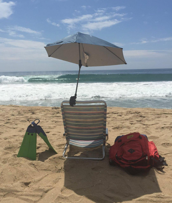 Reviewer image of umbrella clamped to a plastic chair on a beach