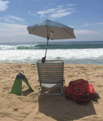 Reviewer image of umbrella clamped to a plastic chair on a beach 