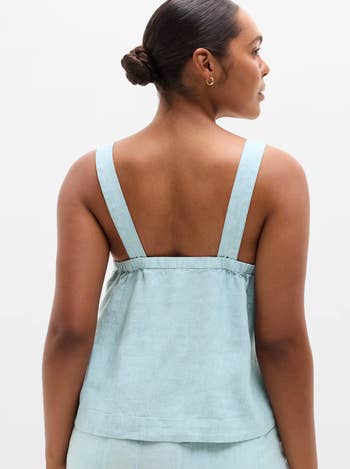 model successful a sleeveless, relaxed-fit apical with wide straps, viewed from the back. Hair styled successful a bun
