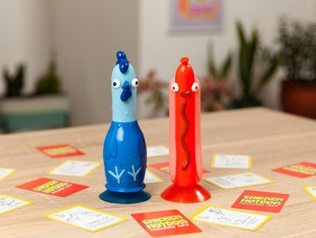 the chicken and the hot dog sitting on a table surrounded by game cards