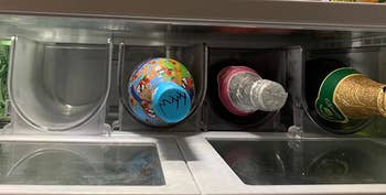 Reviewer image of four clear wine holders in the fridge with bottles