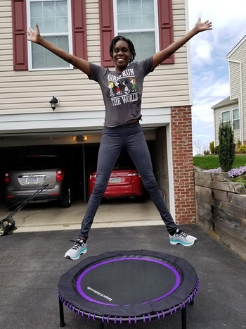 reviewer jumps on black and purple fitness trampoline in their driveway