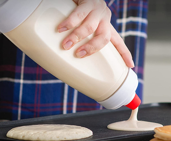 Model pouring pancakes out with handheld bottle-shaped dispenser 