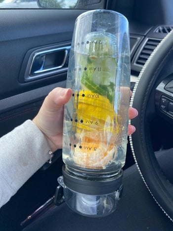 reviewer holding the fruit-infuser water bottle upside down to show that it doesn't leak
