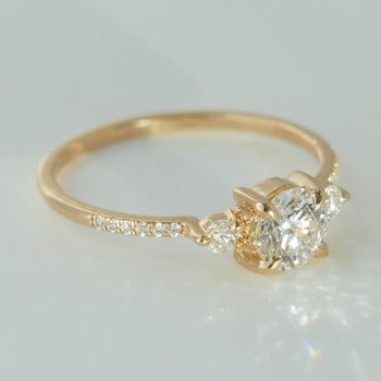 a thin gold band on it featuring diamonds along it, two small round stones and one middle stone