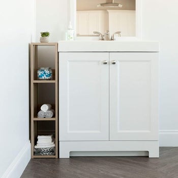 the slimmer, lighter shelving unit next to a sink in a bathroom