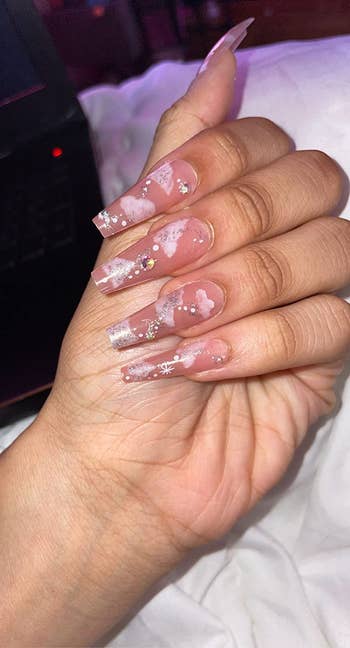 reviewer showing off pink nails with white clouds and glitter