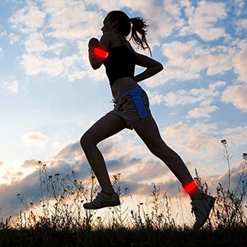 another model wears the same bands in red on arms and ankles while running at sunset