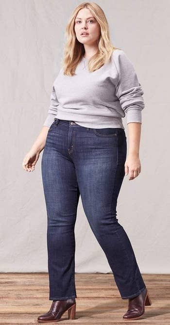 model wearing the jeans in a darker wash with a gray pullover