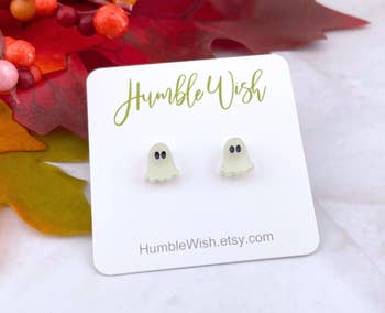 Ghost-shaped earrings displayed connected a card, with a fall-themed inheritance featuring leaves and berries