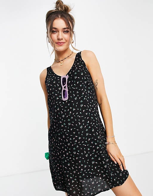 a model in the black shift dress with tiny pink flowers on it