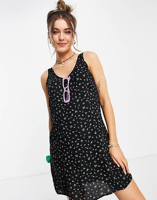 a model in the black shift dress with tiny pink flowers on it
