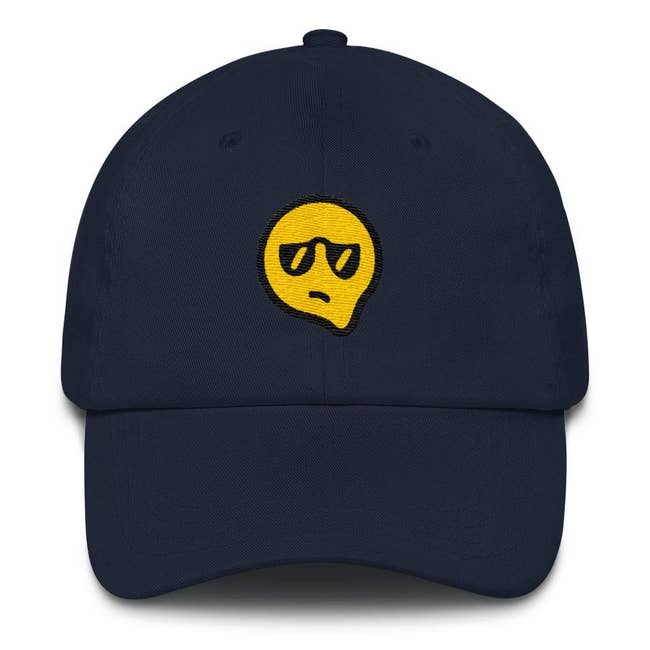 navy cap with melting yellow face wearing sunglasses and a displeased expression