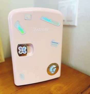 A compact, pink mini-fridge with decorative stickers, ideal for skincare or small item storage