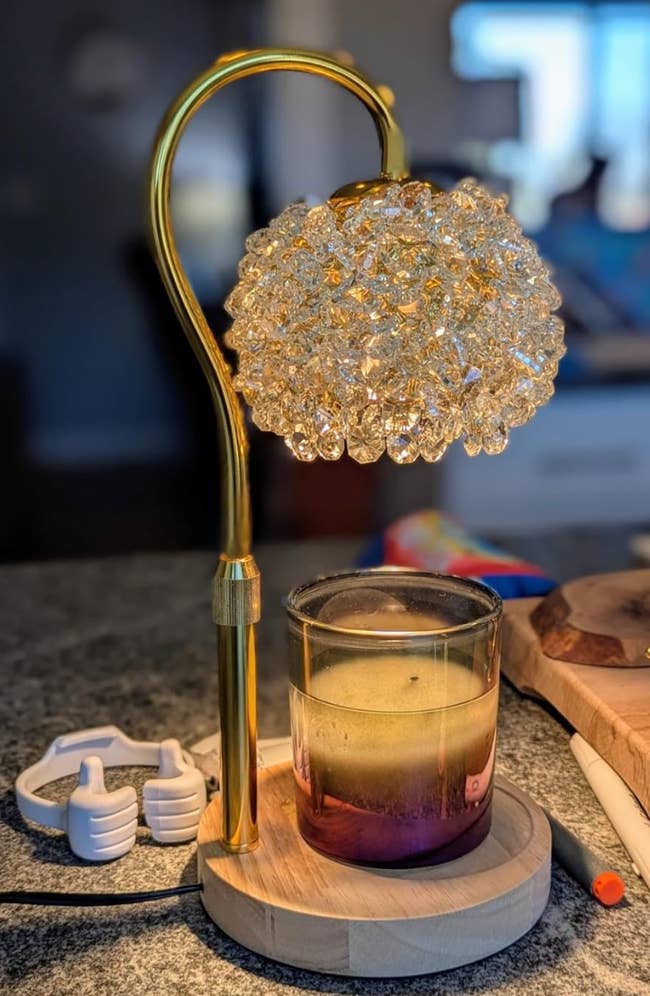 Ornate solid  lamp with a floral plan  supra  a candle connected  a woody  base, placed connected  a countertop with tiny  accessories disposable   nearby