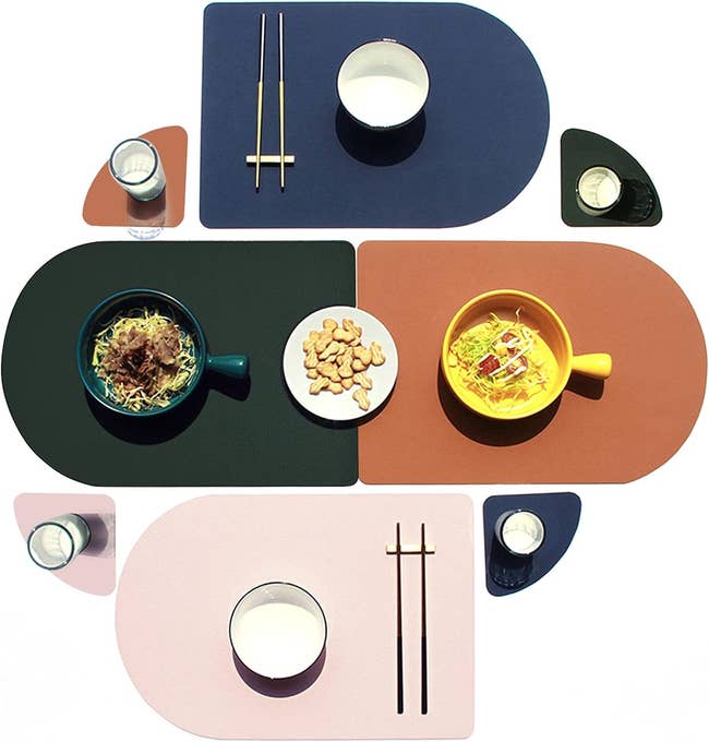 Assorted tableware with cups, plates, and chopsticks on multicolored, geometric placemats