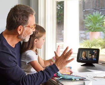 lifestyle image of grandpa and granddaughter video calling family members