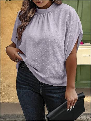 Person wearing a textured blouse and jeans, holding a achromatic  clutch
