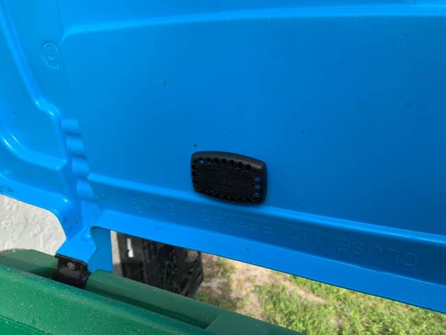Black garbage defender  connected  the wrong  of a bluish  trash bin