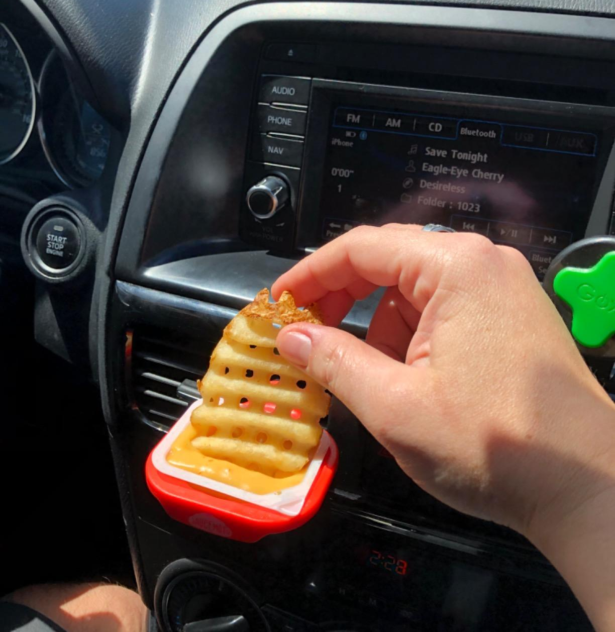 the clip attached to a car vent and a reviewer dipping a waffle fry into sauce