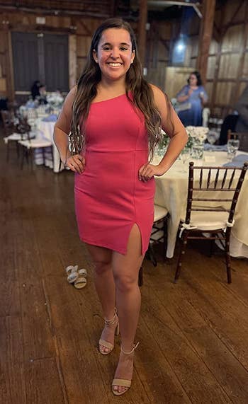 Reviewer wearing mini hot pink bodycon dress with tiny slit on the bottom corner of the dress with nude heels