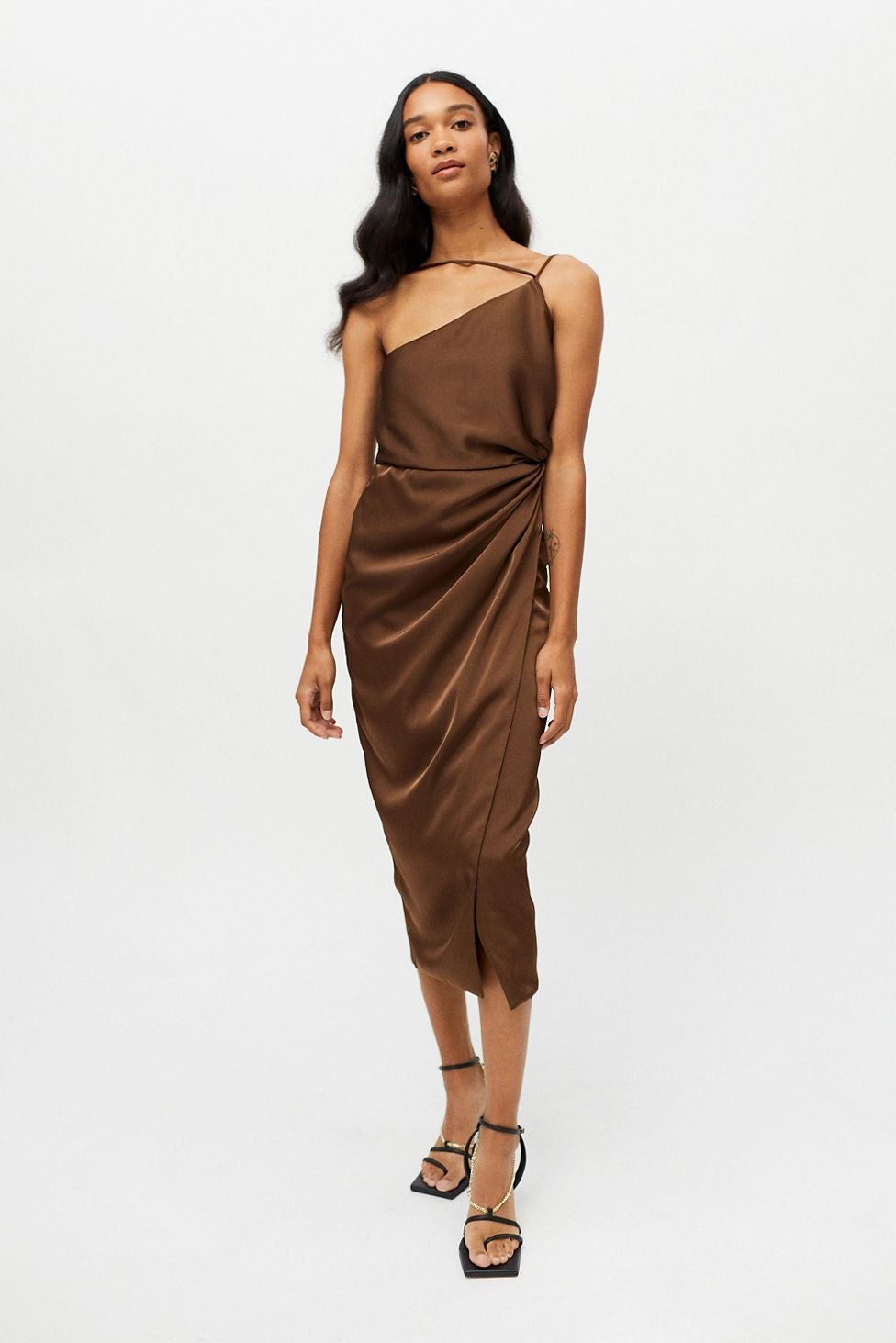 model wearing the brown dress, which has asymmetrical straps across the neckline