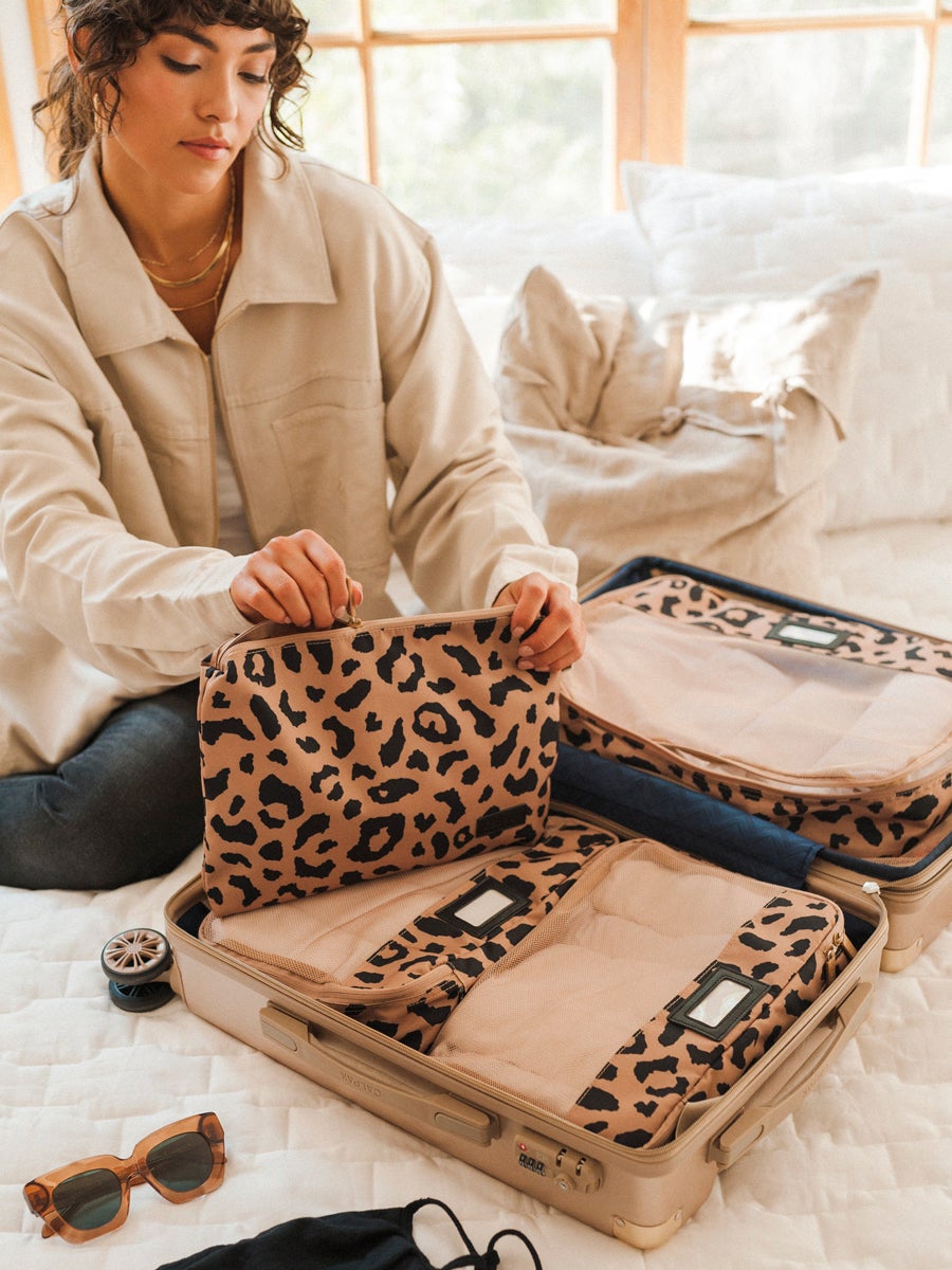 someone using the packing cubes to pack items into their carryon