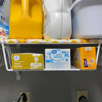 another reviewer's white under-baskets hanging off a laundry room shelf holding additional items