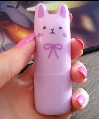 Person holding a cute bunny-shaped lip balm container with painted pink nails