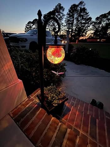 Decorative star  lantern hanging outdoors astatine  dusk, casting lukewarm  airy  implicit    a ceramic  walkway and tiny  potted plant