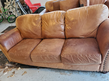 reviewer's brown leather couch that looks faded, cracked, and old
