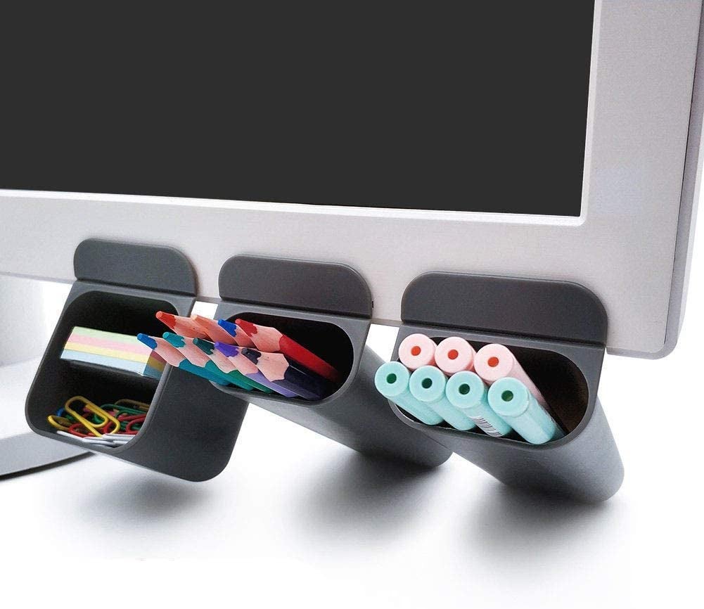 three gray angled holders on bottom of monitor, two small for pens and pencils and one large with a divider for sticky notes and paperclips