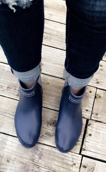 top down view of reviewer wearing the black boots with rolled up jeans