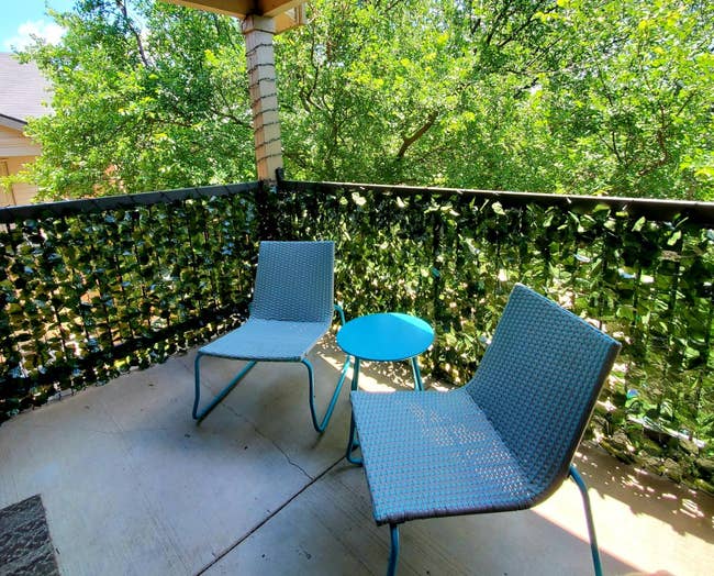 reviewer's balcony decorated with the faux ivy adding privacy to the space