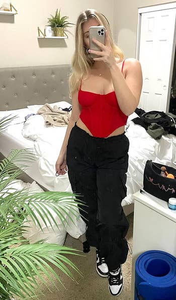 a reviewer wearing the pants in black with a red corset top 