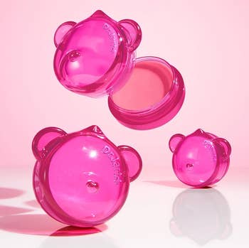 three containers against a pinkish background, 1 unfastened to amusement pinkish balm and creaseless texture
