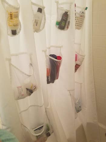 mesh pockets attached to a shower curtain filled with assorted toiletries in reviewer bathroom