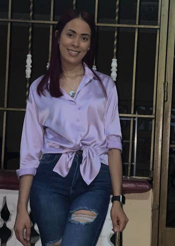 a reviewer wearing in a tied-front lavender blouse and distressed jeans