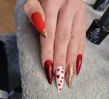 reviewer showing their nails painted with the festive red, gold, and white gel polishes