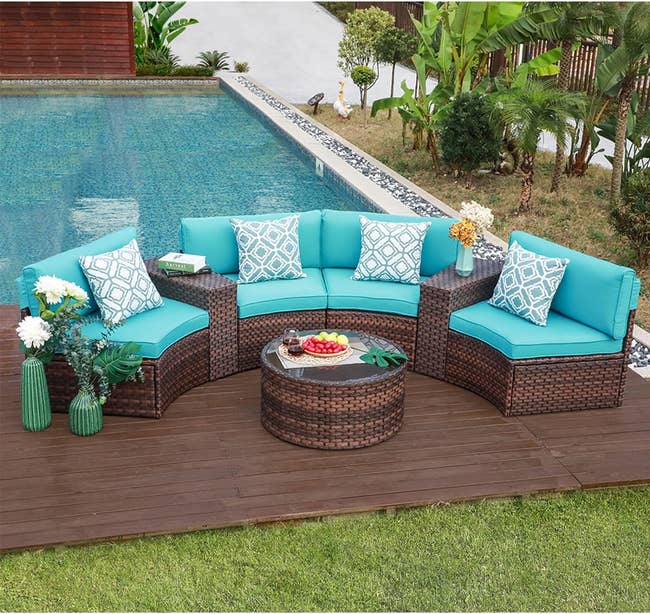 Outdoor sectional sofa set with turquoise cushions, arranged on a deck beside a pool, with accent pillows and a central round table